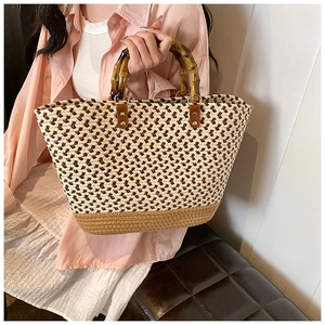 Detail of a woven tote bag with bamboo handles and cream brown textured fabric