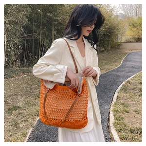 Detail of orange woven tote bag with brown leather straps and mesh pattern for summer fashion
