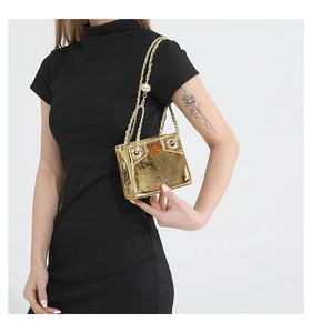 Detail of trendy gold metallic mirror PU bag with chain strap worn by a female model