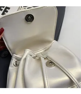 Detailed macro view of magnetic clasp and pearl white textured leather on drawstring bag