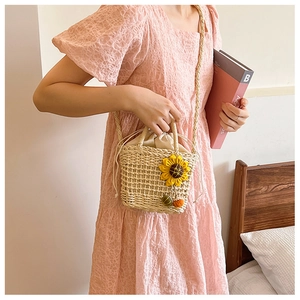 Detail of straw bucket bag featuring handmade sunflowers and cotton drawstring closure