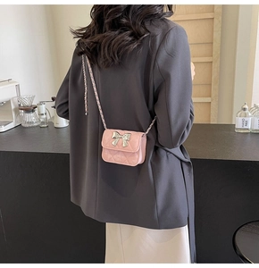 Pink quilted crossbody bag with silver bow accent shown on a model in a cafe