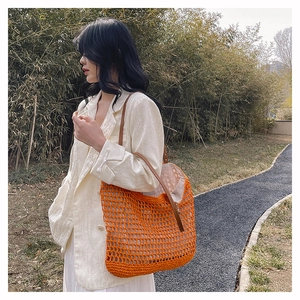Close-up of orange crochet woven tote bag with brown leather straps and inner lining