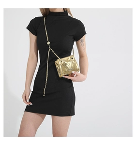 Detail of gold metallic crinkled leather chain bag with silver brand logo on black dress