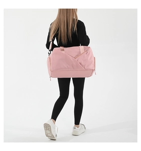 Pink waterproof nylon gym bag with adjustable strap and multi-pocket detail on shoulder