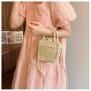 Detail of straw woven handbag with drawstring inner bag and elegant wooden texture handle