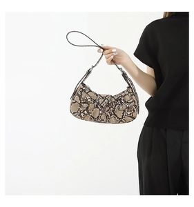 Detail shot of snakeskin print faux leather underarm bag with metal buckle accent