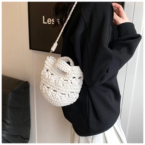 Close-up of white handcrafted crochet knit bucket bag with thick textured woven patterns