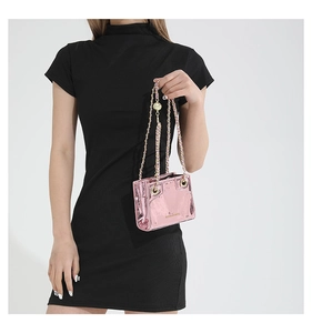 Close-up of metallic pink mini chain bag with gold woven strap worn by a model