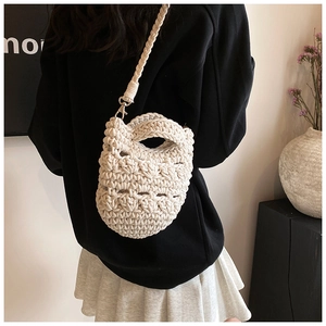 Detail of beige hand-knitted crossbody bag with hollow patterns and braided strap