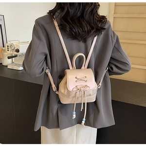 Detailed back view of a light pink mini drawstring backpack with bow and beaded details