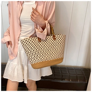 Detail of woven tote bag featuring natural bamboo handles and silver rivet leather accents
