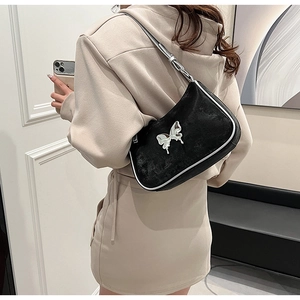 Détail d'un sac sous le bras en PU noir avec boucle papillon argentée sur un mannequin