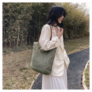 Detailed texture of green woven shoulder bag with brown leather strap in a natural garden