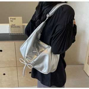 Detail of silver metallic hobo bag featuring stylish drawstring bow and textured leather