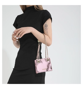 Detail view of pink metallic PU shoulder bag with elegant chain strap on a model