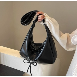 Detail of black PU leather crescent handbag with lace-up bow and wide shoulder strap
