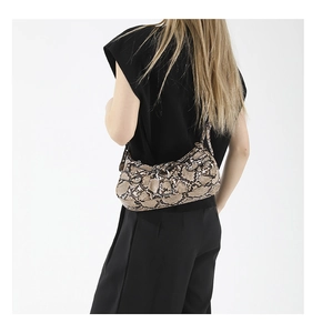 Detail view of snakeskin pattern shoulder bag with silver buckle on a model