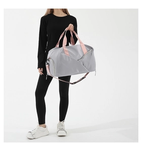 Woman carrying large light grey nylon gym bag with pink straps and adjustable shoulder belt