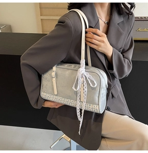 Detail of silver PU leather handbag featuring floral trim and a white lace bow decoration