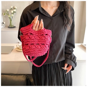 Detail of fuchsia hand-woven knit crossbody bag with hollow-out texture and metal D-ring
