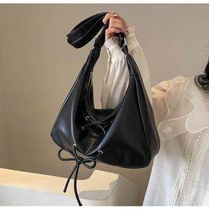 Detail of black PU leather hobo bag featuring a decorative bow knot and smooth texture