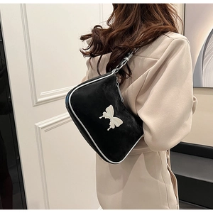 Détail d'un sac sous le bras en PU noir avec fermoir papillon argenté porté par un modèle