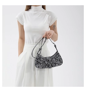 Detail of snake print faux leather texture and silver studs on trendy shoulder bag