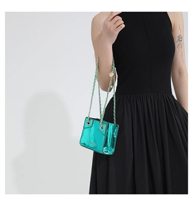 Detailed close-up of metallic teal PU handbag with golden chain strap and round charm