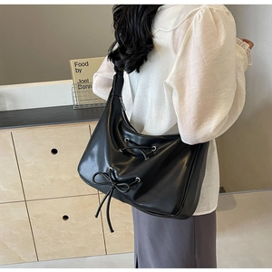 Detail view of black PU leather shoulder bag featuring a stylish decorative bow and metal ring