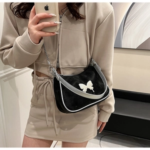 Détail du sac sous l'aisselle en peluche noire avec papillon blanc et chaîne en métal