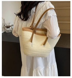 Close-up of woven straw tote bag with brown leather straps and detailed texture