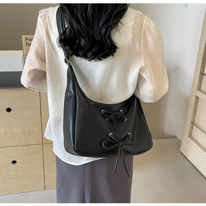 Close-up of a black PU leather hobo bag featuring lace-up details and a cute bow