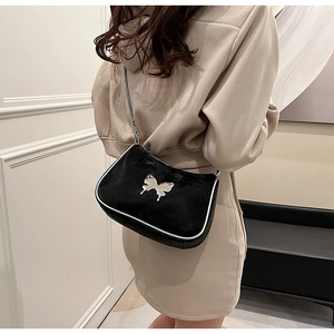 Détail du sac bandoulière noir avec papillon argenté et bandoulière chaîne sur modèle