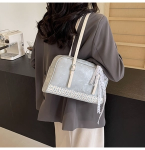 Detail of light blue PU handbag featuring floral patchwork and a large lace bow pendant