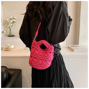 Detailed view of hand-woven fuchsia knit crossbody bag with thick cotton rope texture
