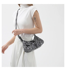 Fashionable snake print shoulder bag detail shown on a model with white outfit