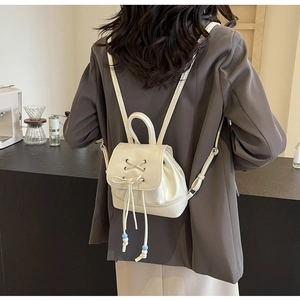 Detailed view of cream PU leather mini backpack with cross-stitch and bead drawstring