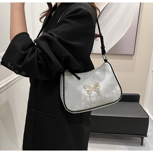 Gros plan sur un sac à bandoulière argenté métallisé avec un grand motif papillon en métal