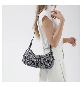 Detail of snake print PU leather shoulder bag with silver studs and rivets on model
