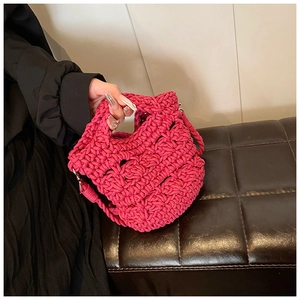 Detail of rose red knit crossbody bag with chunky hand-woven texture and metal buckle