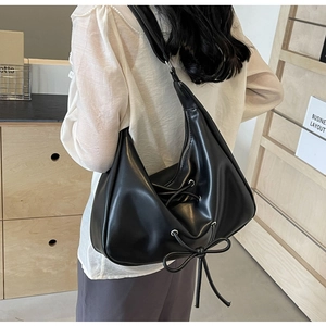Detail of minimalist black PU leather hobo bag with trendy bow ribbon and wide strap