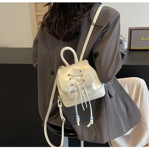 Mini cream PU leather backpack with ribbon bow detail shown in lifestyle setting