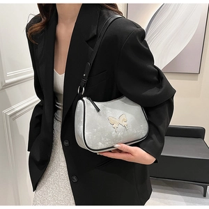 Détail du sac demi-lune argenté avec papillon crème et bandoulière noire réglable