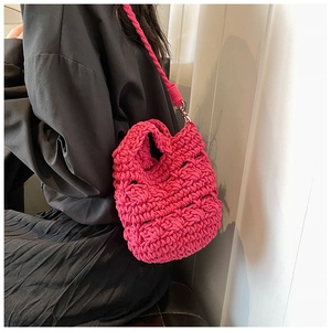 Detailed close-up of vibrant rose red knit crossbody bag with woven shoulder strap