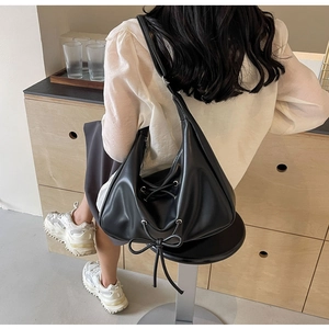 Detail view of black PU leather half-moon shoulder bag with bow and drawstring closure