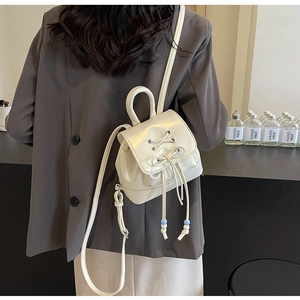 Close-up of pearl white PU leather mini backpack with decorative eyelets and drawstring bow