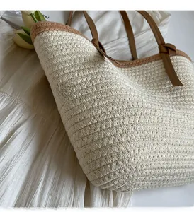 Close-up of woven straw tote bag featuring brown leather handles and beige fiber texture