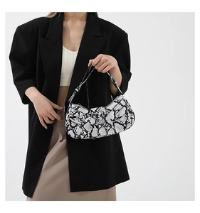 Detail of snake print shoulder bag with silver buckle worn on a black blazer