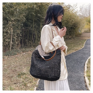 Detail of black woven crochet tote bag with brown straps in a scenic outdoor setting